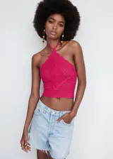 Top de crochet color fucsia, con diseño crop, cuello halter y cierre de lazo en el cuello.