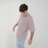 Remera color crema de corte holgado con cuello redondo y mangas cortas. Estampado pequeño en el pecho con texto en azul y amarillo.