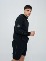 Campera deportiva Umbro modelo Terrace, color negro, con capucha y cierre frontal completo. Cuenta con bolsillos tipo canguro y detalles de la marca en las mangas.