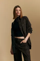 Sobrecamisa de efecto engomado en color negro, con textura lavada, cuello clásico, cierre frontal con botones a tono y bolsillos frontales con solapa.