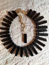 Collar corto de obsidiana natural con piezas rectangulares negras, cadena de extensión dorada y dije colgante de piedra.