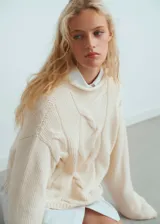 Chaleco de punto grueso con diseño trenzado, cuello perkins y corte oversize.