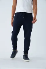 Pantalón deportivo de felpa en color azul marino, con cintura elástica ajustable mediante cordón, bolsillos laterales con cierre y puños con cierre en los tobillos.