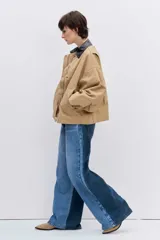 Cazadora de corte oversize en color beige, con cuello de solapa en contraste de color oscuro, cierre frontal con botones y bolsillos laterales.