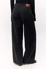 Pantalón de denim fino color negro con un dejo de marrón, tiro medio y pata ancha con costuras a contratono.