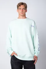 Buzo color verde agua de corte oversize con cuello redondo, confeccionado en tela rústica y con estampa en el pecho y en la manga.