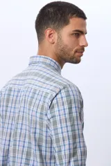 Camisa sport de manga larga con estampado de cuadros en tonos azules, grises y blancos. Presenta cuello con botones, cierre frontal abotonado y un bolsillo pequeño en el pecho.