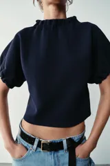 Top de punto color azul marino, con cuello redondo y mangas cortas abullonadas con acabados elásticos fruncidos.