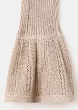 Cardigan de punto fino color beige, entallado, con cuello en V, manga larga acampanada, bajo con volante y cierre frontal con botones.