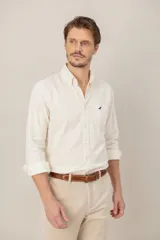 Camisa de pana color beige, de corte clásico y calce regular, con cuello abotonado, mangas largas, un bolsillo en el pecho con detalle bordado y cierre frontal de botones.