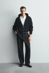 Chaqueta de punto compacto con capucha, confeccionada en hilatura con lana. Presenta cierre frontal con cremallera, mangas largas y acabados en rib.