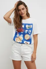 Remera de algodón de manga corta y cuello redondo, con corte holgado. Presenta un estampado frontal que simula un mantel a cuadros azules con ilustraciones de comida y un cangrejo.