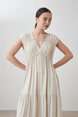 Maxi vestido color beige melange, con escote en V, mangas cortas y falda larga con volantes.