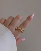 Anillo de acero dorado con diseño cruzado y ajustable.