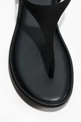 Sandalias planas de dedo color negro, con diseño minimalista y tira fina en el empeine con sujeción trasera elástica.