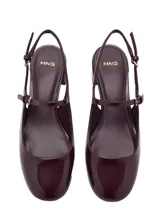 Zapato destalonado de tacón bloque bajo con acabado efecto charol, puntera redondeada y cierre de hebilla ajustable en el tobillo.