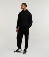 Pantalón jogger negro de algodón y poliéster, con cintura elástica y cordón ajustable. Presenta bolsillos laterales y puños ajustados en los tobillos.