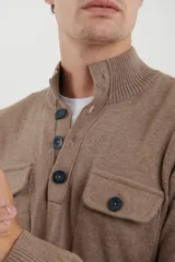 Sweater azul con cuello alto abotonado y dos bolsillos frontales con botón.