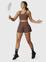 Falda skort deportiva color chocolate con short integrado, confeccionada en tejido técnico de secado rápido con borde inferior en contraste blanco.
