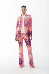 Pantalón de vestir con leve evasé y tajo en laterales, con estampado de flores grandes en tonos violeta y naranja.