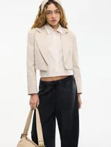 Chaqueta cropped color beige con solapa en la delantera y camisa desmontable de manga larga color rosa pálido.