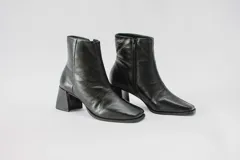 Botas de cuero negro con caña corta, cierre lateral con cremallera, punta cuadrada y tacón geométrico.