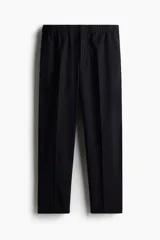 Pantalón negro de corte relajado, confeccionado en tejido suave. Presenta cintura elástica con cordón oculto, cierre con botón y corchete, bolsillos laterales y bolsillos insertados traseros. Las piernas son ajustadas y tienen pliegues marcados.