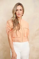 Chaqueta bomber color durazno con cierre frontal y bolsillos grandes con cierre. Mangas cortas con ajuste mediante lazos.