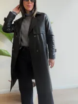 Trench de ecocuero negro con diseño cruzado de doble abotonadura, solapas clásicas, puños ajustables y largo midi.