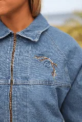 Campera de jean con mangas de denim azul y espalda con tejido estampado de motivos étnicos en tonos tierra, verde y azul.