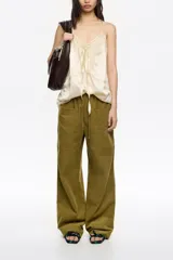 Pantalón de corte recto y tiro bajo, color crudo, con bolsillos frontales tipo alforja y cintura ajustable con cordón.