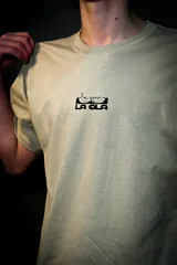 Remera de corte holgado color verde militar, con cuello redondo y mangas cortas. Presenta un pequeño estampado negro en el pecho y un diseño gráfico vertical en la espalda con tipografía y el texto "by riders for riders".