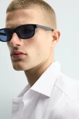 Camisa de corte slim fit confeccionada en tejido de algodón con textura. Presenta cuello italiano, manga larga con puños abotonados y cierre frontal de botones.