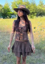 Falda corta color marrón con diseño de volados escalonados y short interior incorporado. Presenta una textura sutilmente rayada y una silueta liviana y fluida.