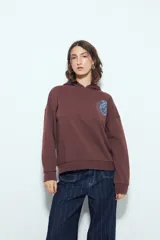 Buzo canguro color marrón con capucha y estampado de un corazón anatómico en azul en el pecho. De silueta relajada y calce cómodo.