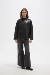 Sobrecamisa de cuero sintético en tono bordó oscuro, con cuello clásico, cierre frontal oculto y un bolsillo aplicado en el pecho. Presenta un corte holgado con mangas largas y puños rectos.