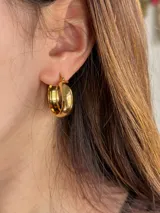 Aros de acero quirúrgico dorado con diseño abombado, cierre criollo y tamaño mediano.
