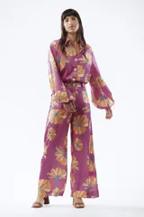 Pantalón de mujer con estampado de flores grandes color naranja sobre fondo fucsia. El pantalón es de corte palazzo y tiro alto.