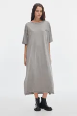 Vestido midi gris con efecto washed, cuello redondo, manga corta, corte recto y holgado, con pequeños tajos laterales en el bajo y un parche bordado en el pecho.