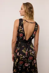 Vestido largo de gasa estampada con flores, con escote en V profundo y detalles de cuero ovino en los bordes y cintura. Presenta dos tajos delanteros y tiras ajustables en la espalda.