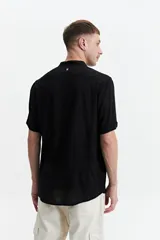 Camisa negra de manga corta con cuello mao y doblez en las mangas.