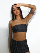 Vestido corto de red con brillos, mangas largas y cuello redondo. Incluye top y short negro.