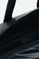 Bolso tipo shopper color marrón con diseño matelassé. Tiene doble asa corta y correa larga desmontable. Incluye llavero de corazón y dijes desmontables, y compartimento interior para notebook.