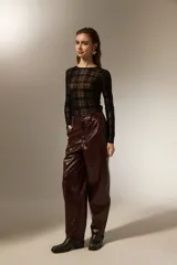 Pantalon de eco-cuero con diseño barrel, de tiro alto y corte holgado. Cuenta con bolsillos laterales y cierre frontal con botón.