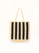 Bolso tipo tote de tejido de rafia con diseño de rayas verticales en colores crudo y negro. Presenta bordes con terminación festoneada y doble asa de hombro.