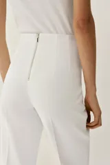 Pantalón de tiro alto en color negro, con diseño de corte recto y ligeramente acampanado. Presenta costuras verticales marcadas en el frente y bolsillos laterales de vivo.