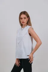Musculosa blanca sin mangas con detalles de bordado inglés y apliques en el pecho.