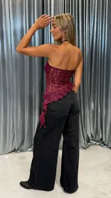 Top strapless de encaje color bordó, con diseño asimétrico y terminación con volados en el ruedo.