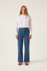 Pantalón de jean azul de tiro medio y corte recto, con terminación desflecada y detalles de trenzas en los laterales.