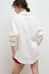 Camisa oversize de lino, color tostado, con cuello clásico, cierre frontal de botones y bolsillo en el pecho.